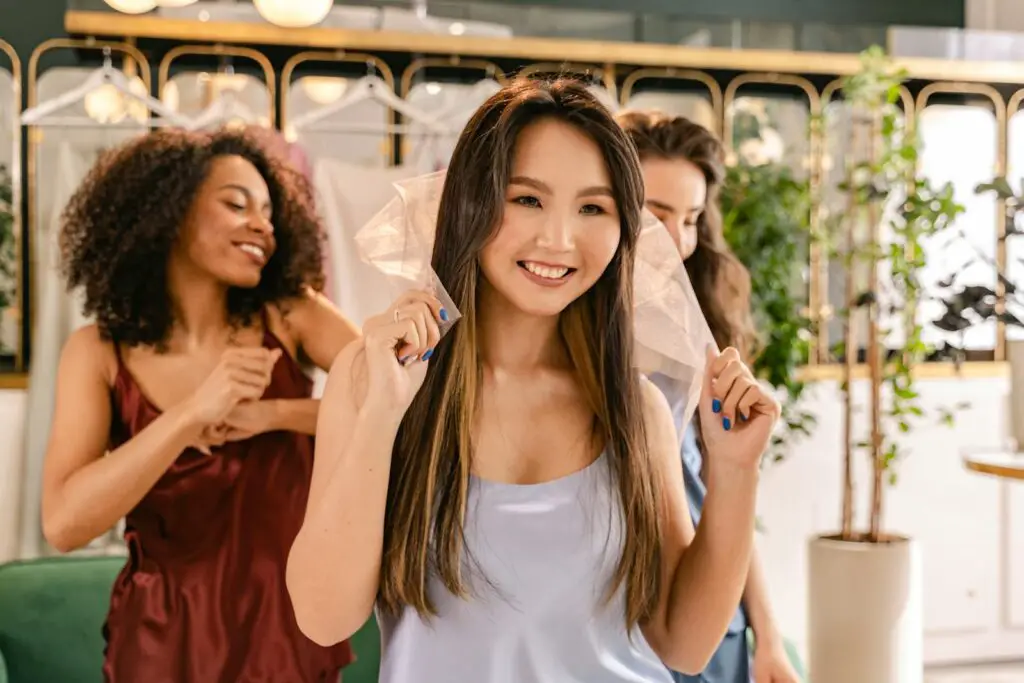 A group of women smiling and having fun during pre-wedding preparations indoors.